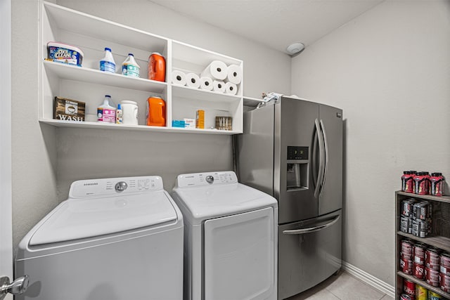 washroom with laundry area, light tile patterned floors, baseboards, and separate washer and dryer