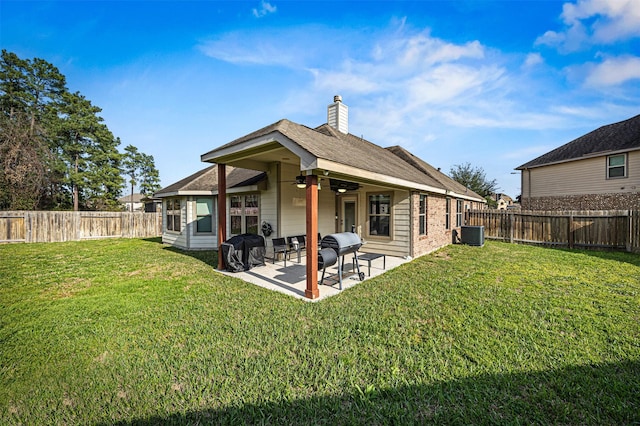 rear view of property featuring a yard, a fenced backyard, a chimney, and a patio