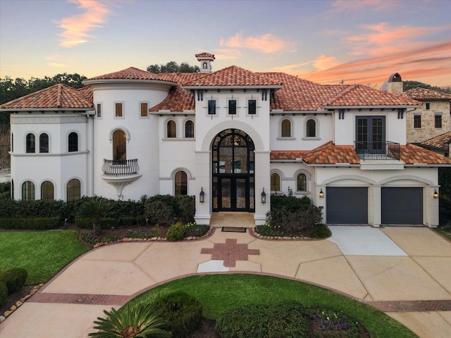 mediterranean / spanish-style house with a garage, french doors, and a balcony