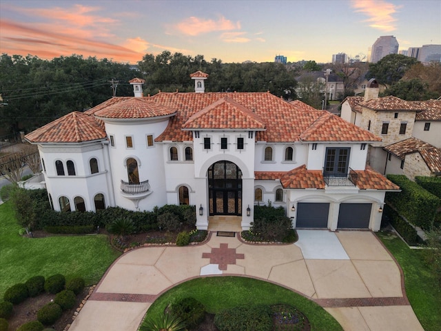 mediterranean / spanish-style house with a balcony, french doors, a garage, and a lawn