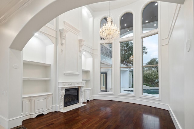 unfurnished living room featuring a premium fireplace, dark wood-type flooring, built in features, and a high ceiling