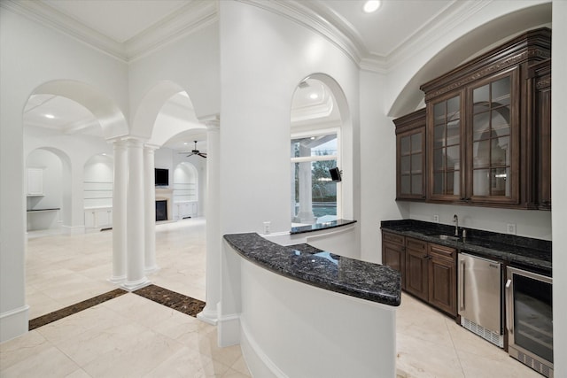 bar with fridge, dark brown cabinets, crown molding, and beverage cooler