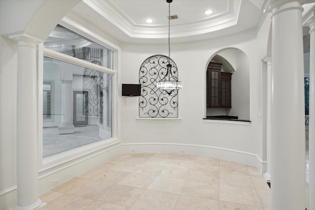 unfurnished room featuring a raised ceiling, crown molding, and ornate columns