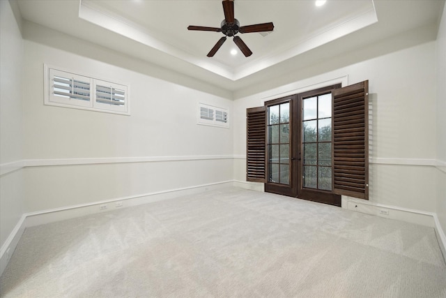 carpeted spare room with crown molding, french doors, a tray ceiling, and ceiling fan