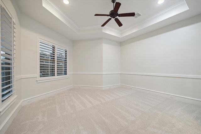 carpeted spare room with ceiling fan, crown molding, and a raised ceiling