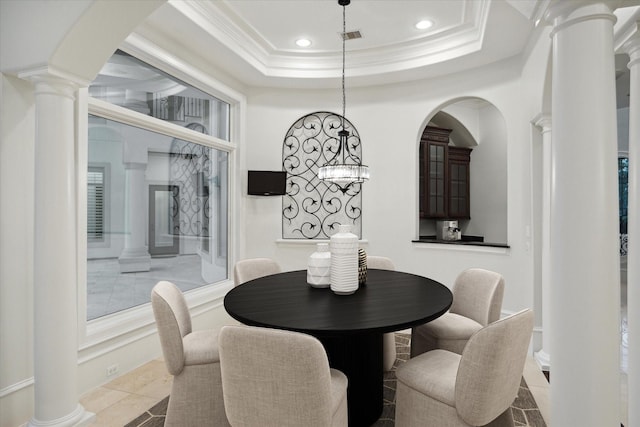 dining area featuring tile patterned floors, ornamental molding, ornate columns, and a raised ceiling