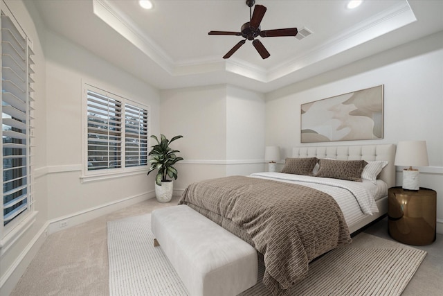 bedroom featuring crown molding, a tray ceiling, light colored carpet, and ceiling fan