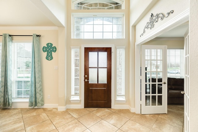 tiled entryway with a high ceiling, crown molding, and french doors