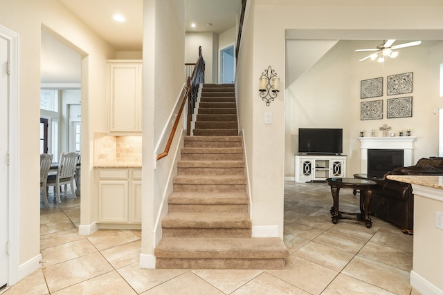 stairway featuring tile patterned flooring and ceiling fan