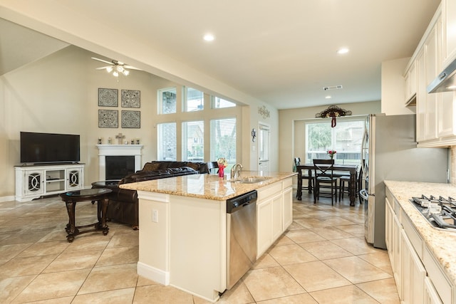 kitchen with a center island with sink, stainless steel appliances, sink, light stone counters, and white cabinets