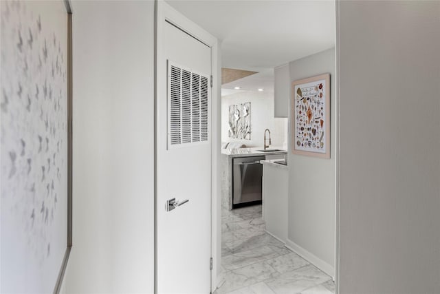 hallway featuring marble finish floor, a sink, and baseboards