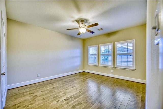 empty room featuring baseboards, ceiling fan, visible vents, and light wood-style floors