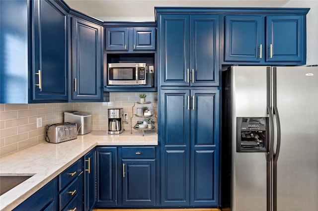 kitchen featuring appliances with stainless steel finishes, blue cabinetry, and backsplash