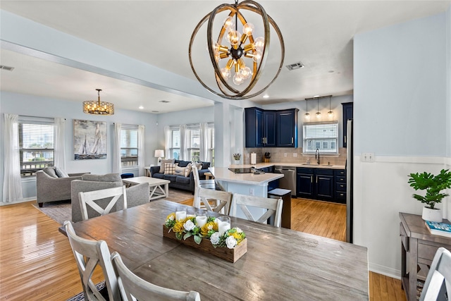 dining area with light wood-type flooring, a chandelier, and sink