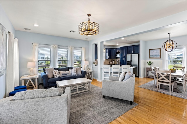 living room with light wood-type flooring, an inviting chandelier, and a wealth of natural light