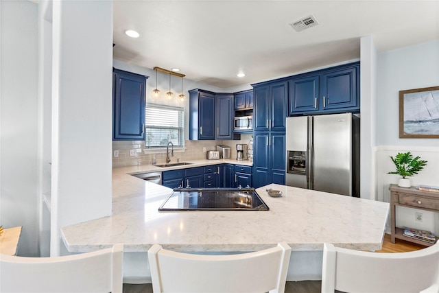 kitchen featuring blue cabinetry, pendant lighting, stainless steel appliances, and a kitchen breakfast bar