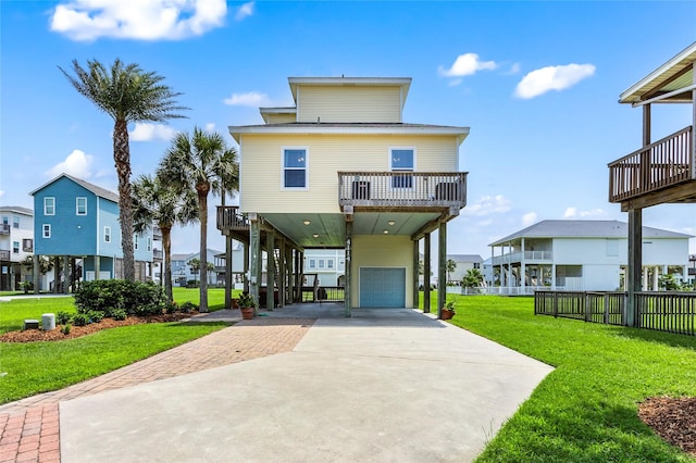 coastal home with a garage, a front lawn, a balcony, and a carport