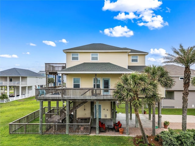 rear view of house featuring a lawn, a wooden deck, and a patio area