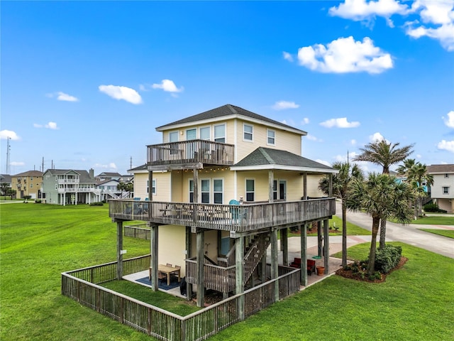 rear view of property with a lawn, a wooden deck, and a patio area