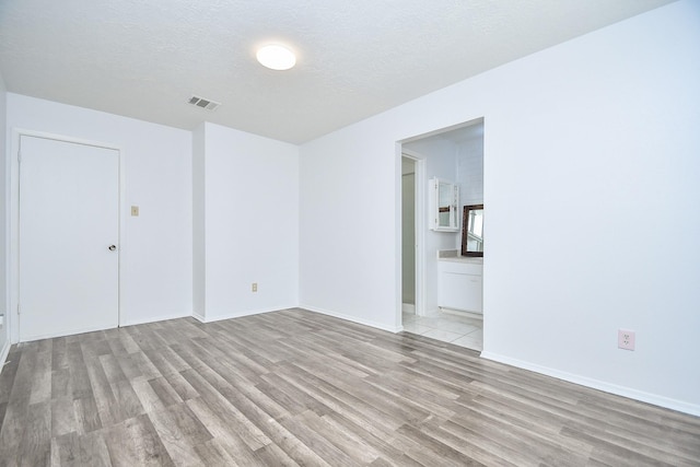 unfurnished room with light hardwood / wood-style flooring and a textured ceiling