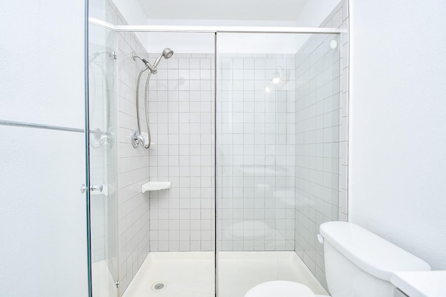 bathroom with a shower with door and toilet