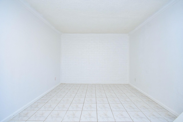 unfurnished room with a textured ceiling, crown molding, and brick wall