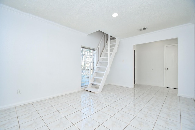 tiled empty room with a textured ceiling and ornamental molding