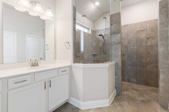 bathroom with lofted ceiling, a tile shower, and vanity