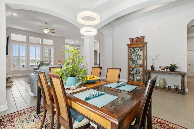 dining room featuring ceiling fan with notable chandelier and light hardwood / wood-style flooring