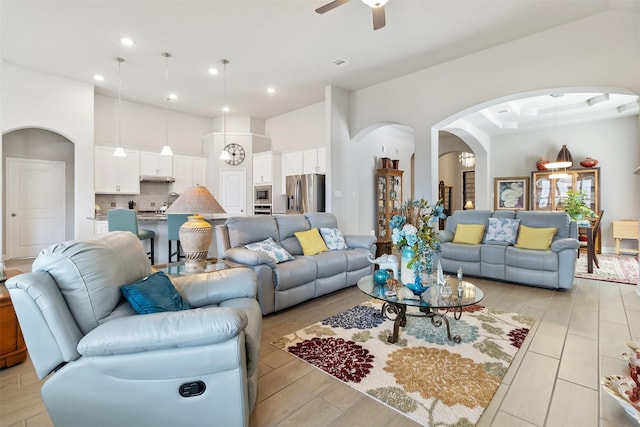 living room with a high ceiling, light wood-type flooring, and ceiling fan