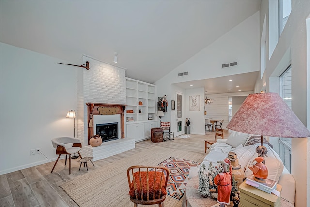 living room featuring a brick fireplace, light wood-type flooring, and high vaulted ceiling