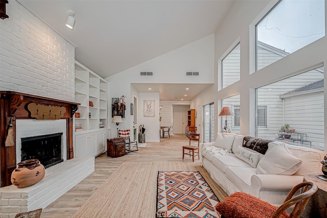 living room featuring light wood-type flooring, high vaulted ceiling, and a fireplace