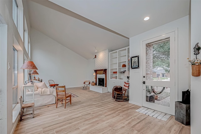 sitting room featuring a fireplace, light wood-type flooring, and vaulted ceiling