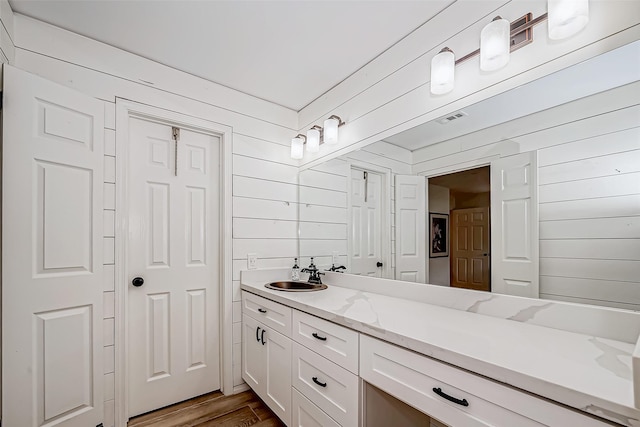 bathroom with hardwood / wood-style flooring, wood walls, and vanity