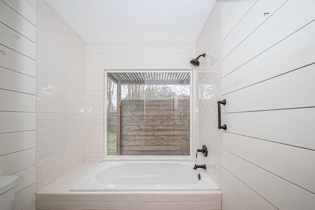 bathroom featuring toilet, tiled shower / bath, and a wealth of natural light