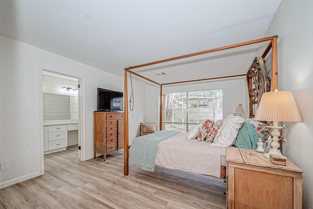 bedroom with light wood-type flooring and ensuite bathroom