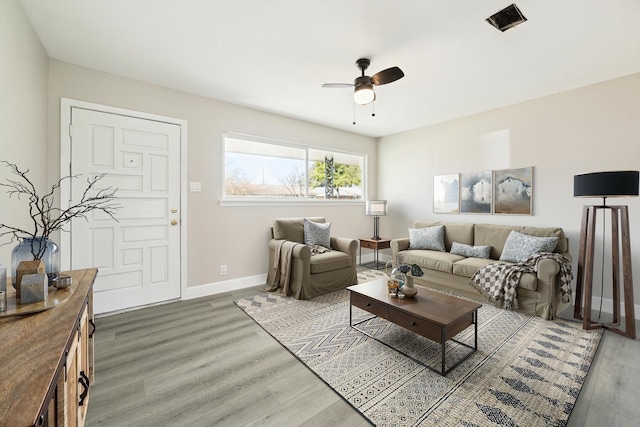 living area featuring dark wood finished floors, a ceiling fan, and baseboards