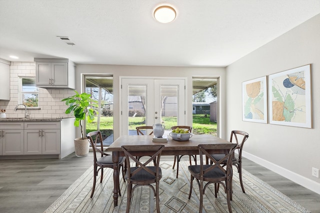 dining room featuring french doors, wood finished floors, a wealth of natural light, and baseboards