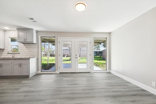 doorway with a healthy amount of sunlight, light wood-style floors, and french doors