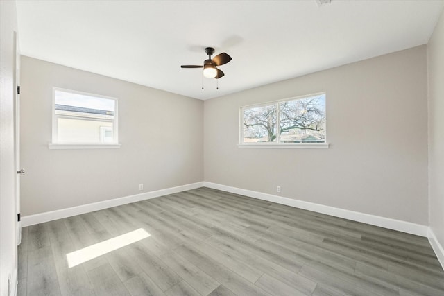 empty room featuring a ceiling fan, baseboards, and wood finished floors