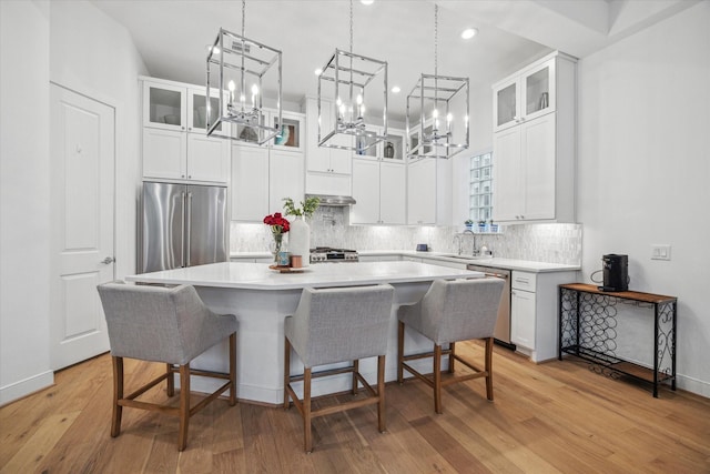 kitchen featuring white cabinets, appliances with stainless steel finishes, glass insert cabinets, light countertops, and a sink