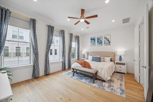 bedroom with light wood finished floors, visible vents, and crown molding