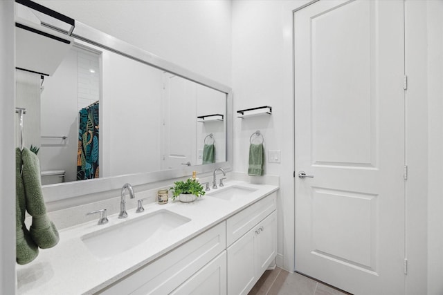 full bathroom with tile patterned flooring, a sink, toilet, and double vanity