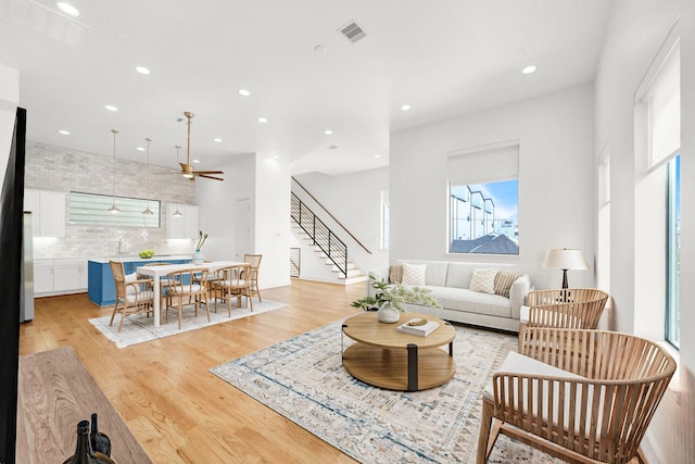 living area featuring recessed lighting, a ceiling fan, visible vents, light wood-style floors, and stairway