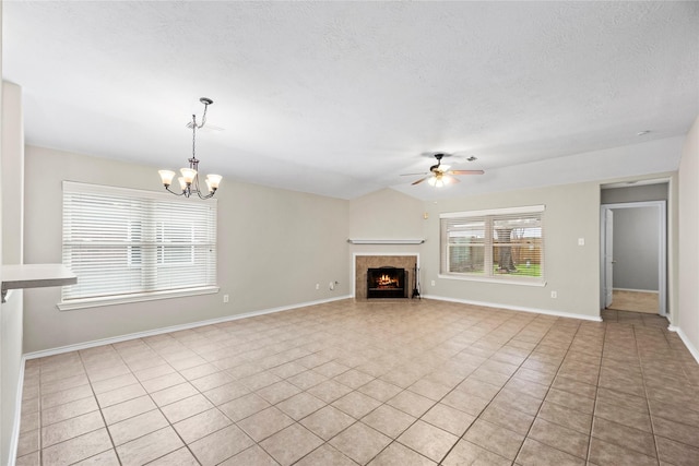 unfurnished living room featuring ceiling fan with notable chandelier, light tile patterned floors, a textured ceiling, and a fireplace