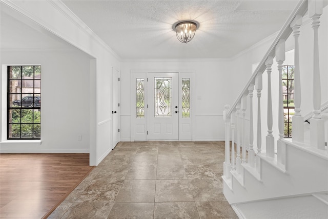 entryway featuring light hardwood / wood-style flooring, crown molding, and a textured ceiling