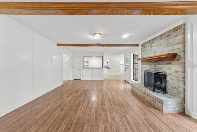 unfurnished living room with light hardwood / wood-style flooring, crown molding, a brick fireplace, and a healthy amount of sunlight