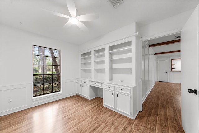 unfurnished office featuring ceiling fan, light hardwood / wood-style flooring, and built in desk