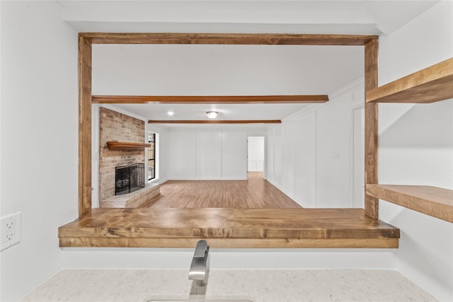 kitchen with white cabinets, light hardwood / wood-style flooring, and a brick fireplace