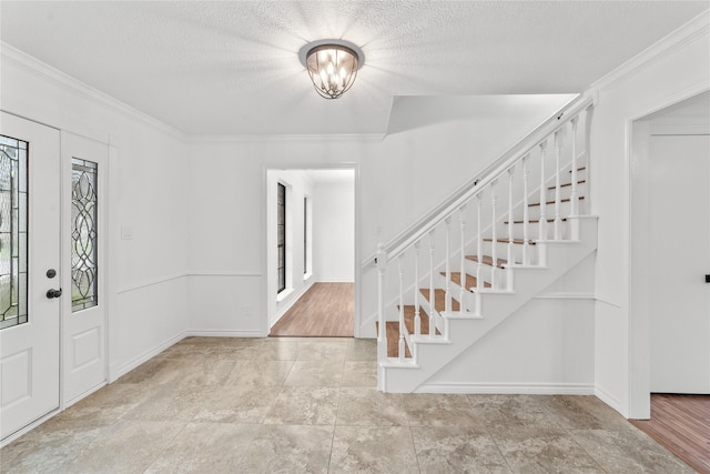 foyer with a textured ceiling, crown molding, and a notable chandelier